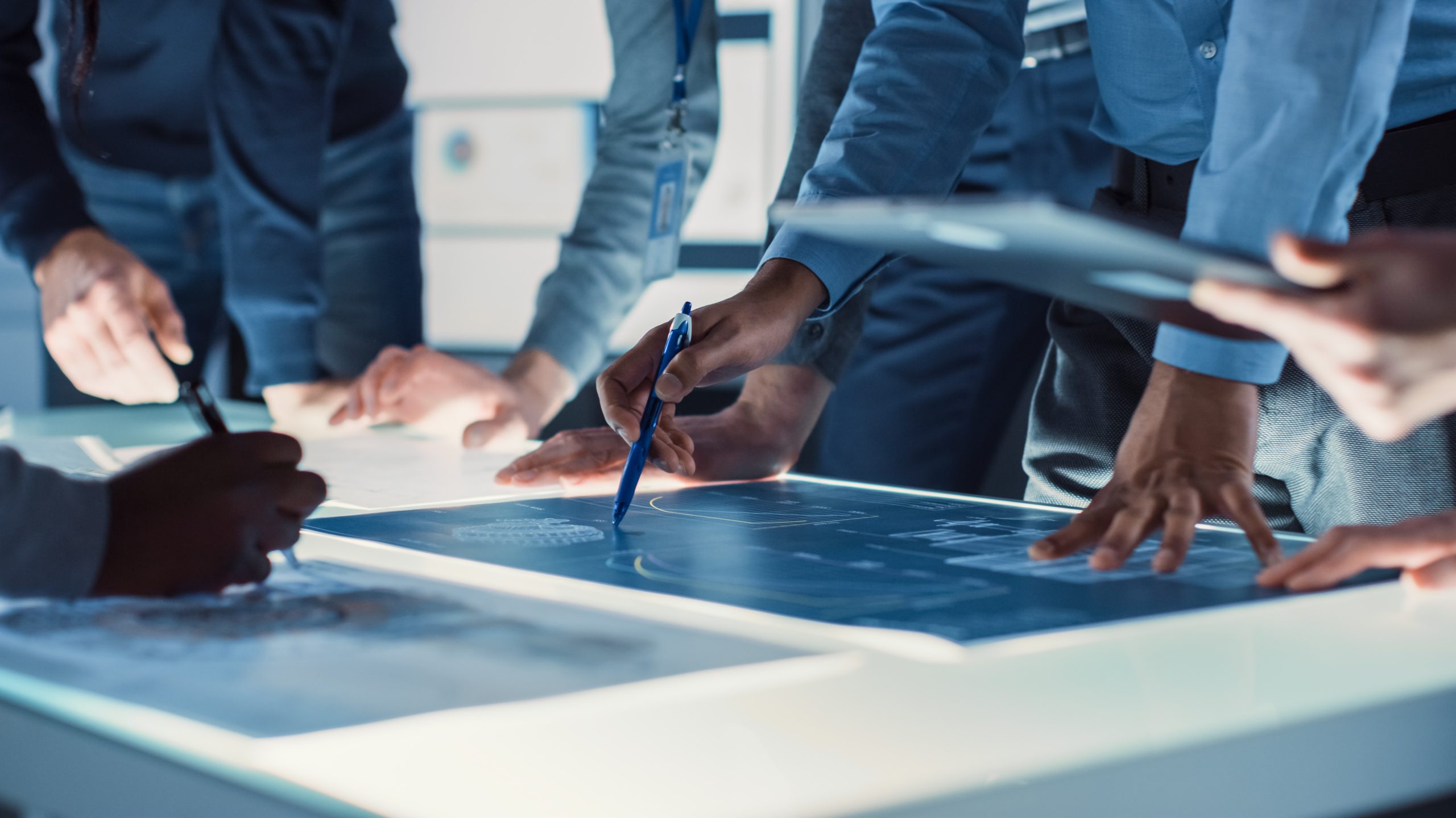 Engineer,,Scientists,And,Developers,Gathered,Around,Illuminated,Conference,Table,In