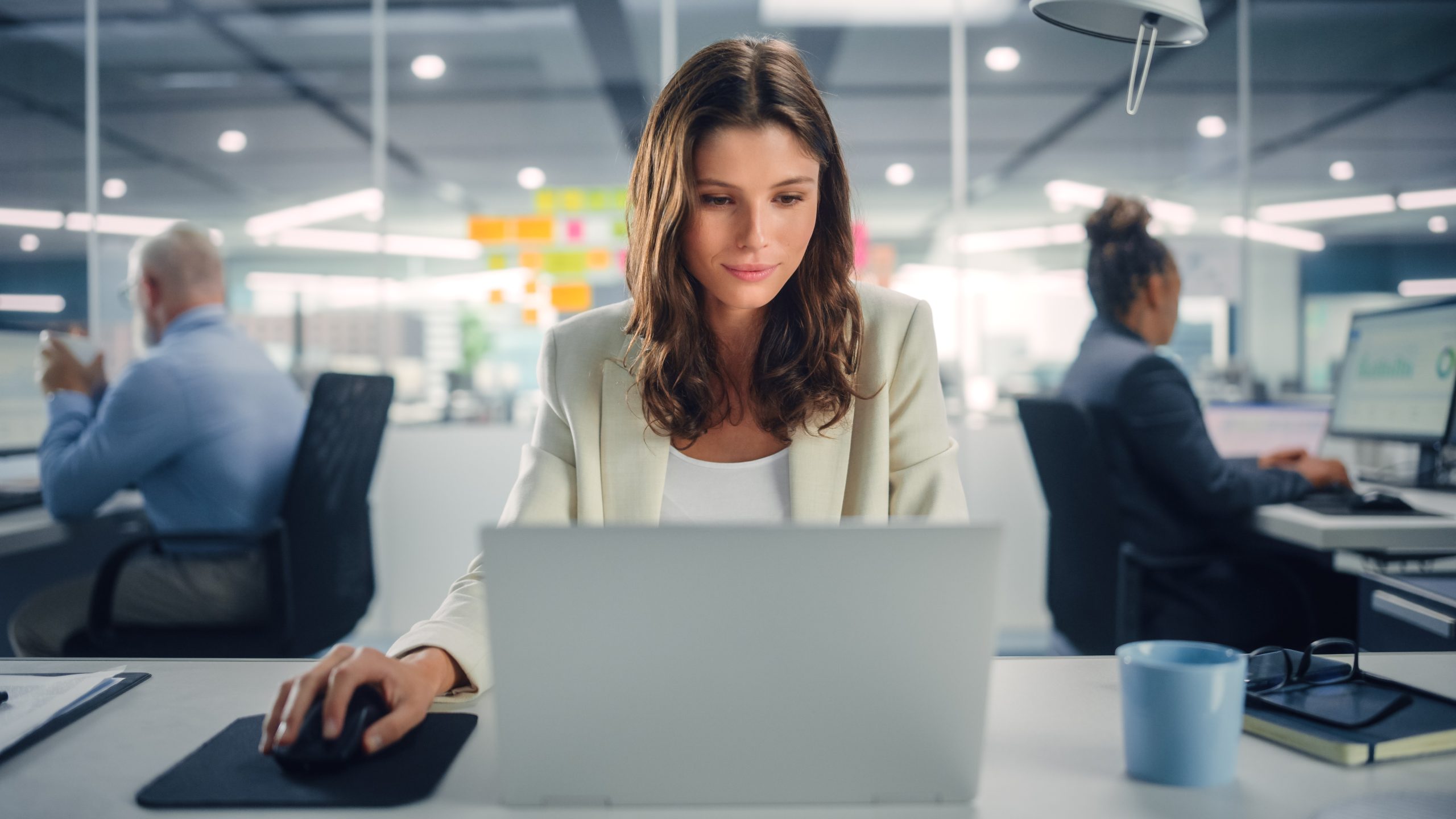 Young,Happy,Businesswoman,Using,Computer,In,Modern,Office,With,Colleagues.