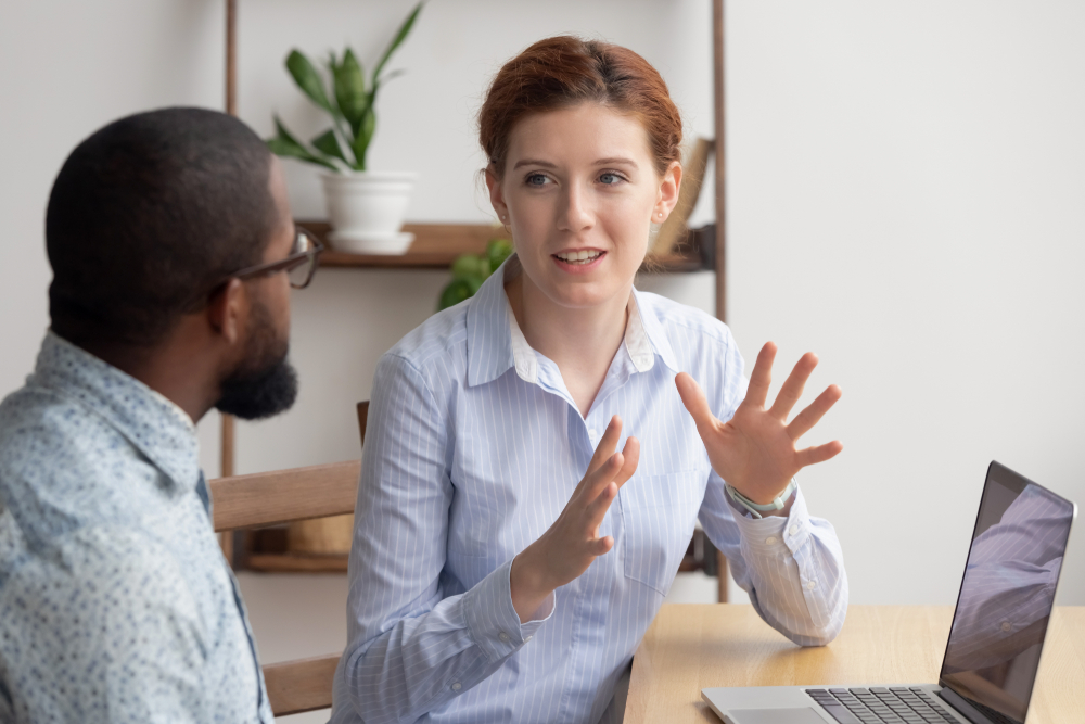 Two,Diverse,Businesspeople,Chatting,Sitting,Behind,Laptop,In,Office.,Excited