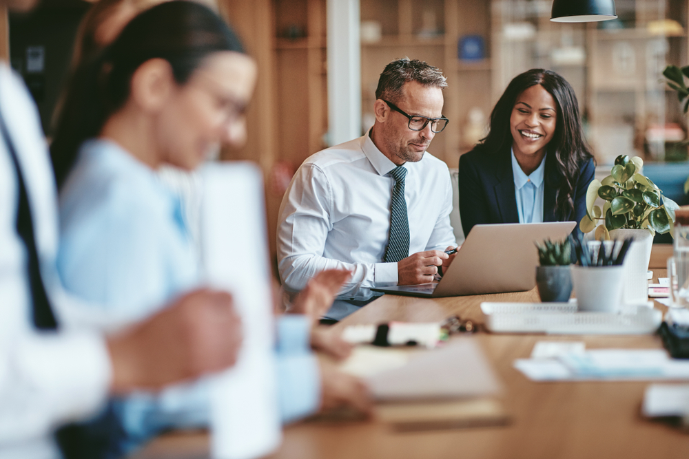 Two,Diverse,Businesspeople,Smiling,While,Working,On,A,Laptop,Together